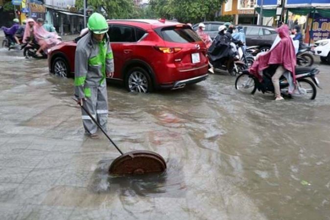 Công nhân Công ty Môi trường Đô thị khơi thông nắp cống thoát nước ven đường ở thành phố Huế