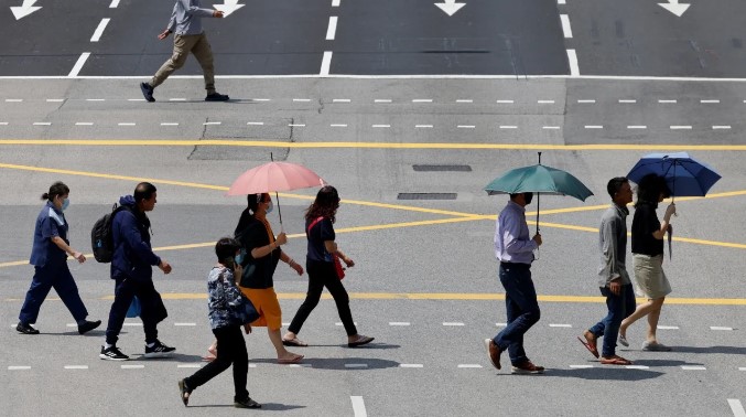 Người dân Singapore dùng ô che nắng khi băng qua đường