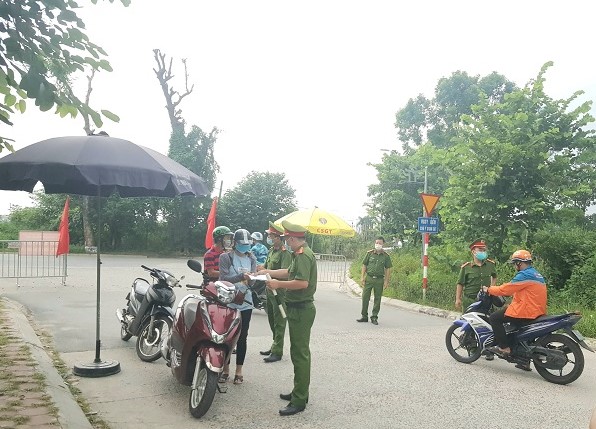 Lực lượng chức năng kiểm tra người dân đi lại tại ngã ba Vân Nội- Đức Thắng, phường Đức Thắng, quận Bắc Từ Liêm. Ảnh: Thiện Tâm.
