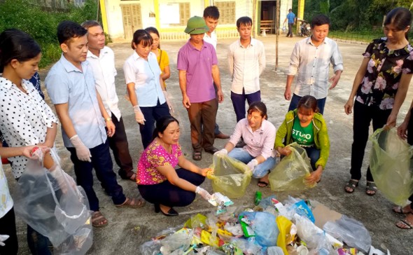 Cán bộ MTTQ xã Hùng Mỹ, huyện Chiêm Hoá, tỉnh Tuyên Quang hướng dẫn người dân phân loại rác thải