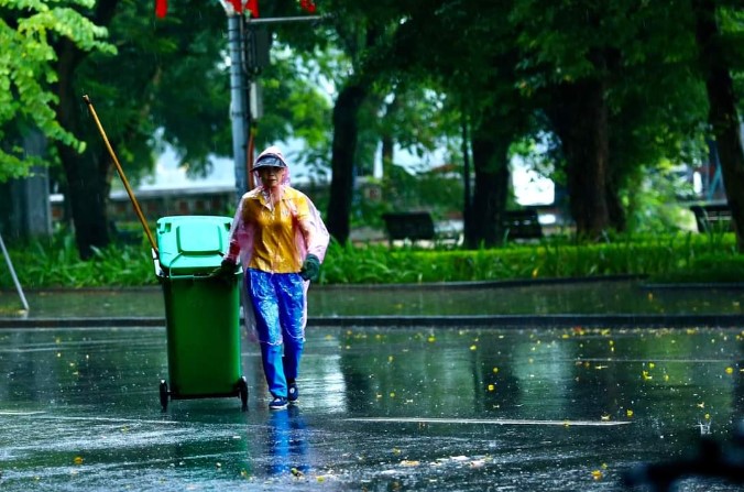 Hình ảnh cô lao công thu dọn rác dưới mưa - Ảnh 1